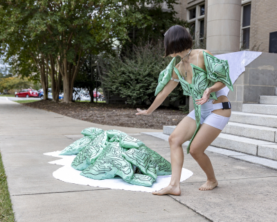 Asian American woman dressed in white and green costume performing outside on East Duke Lawn