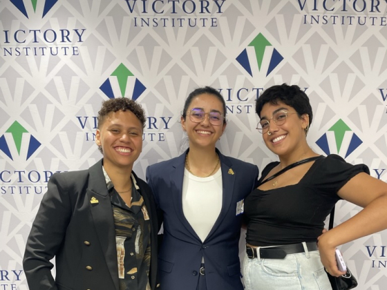 Three women with the Victory Institute backdrop behind them