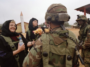 Two nuns offering flowers to two soldiers in full combat gear
