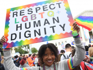 Woman holding "Respect LGBTQ+ Human Dignity" sign